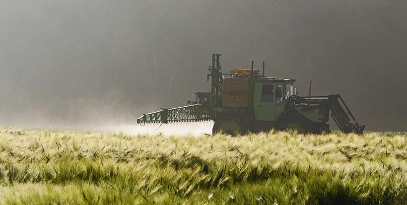 Tracteur difusant des pesticides dans un champs.