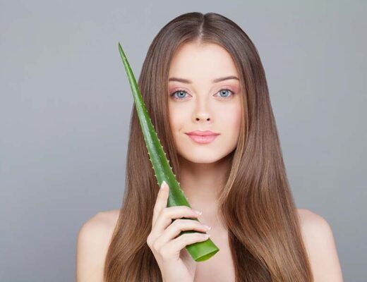 Femme à la peau claire et aux cheveux longs et sains tenant une tige d'aloe vera